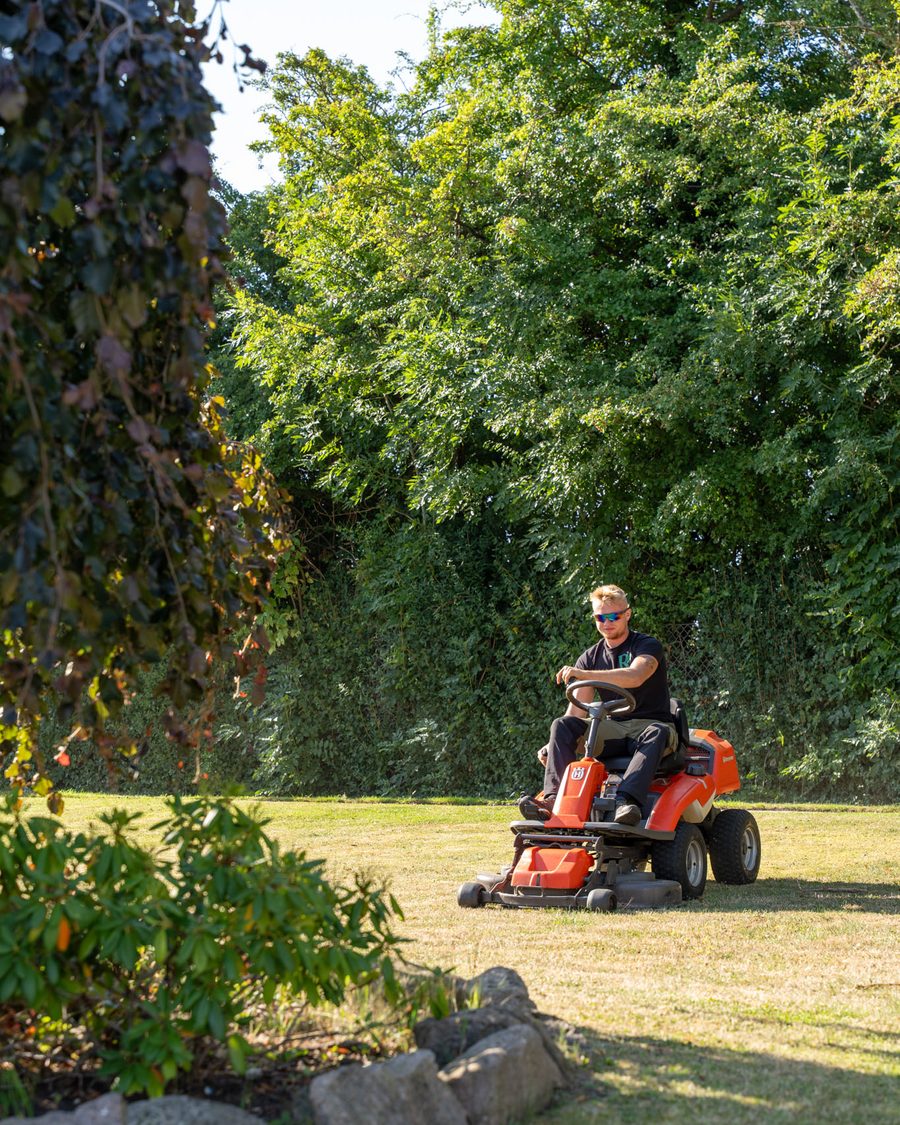 Havetraktor på en grøn plæne i en frodig have